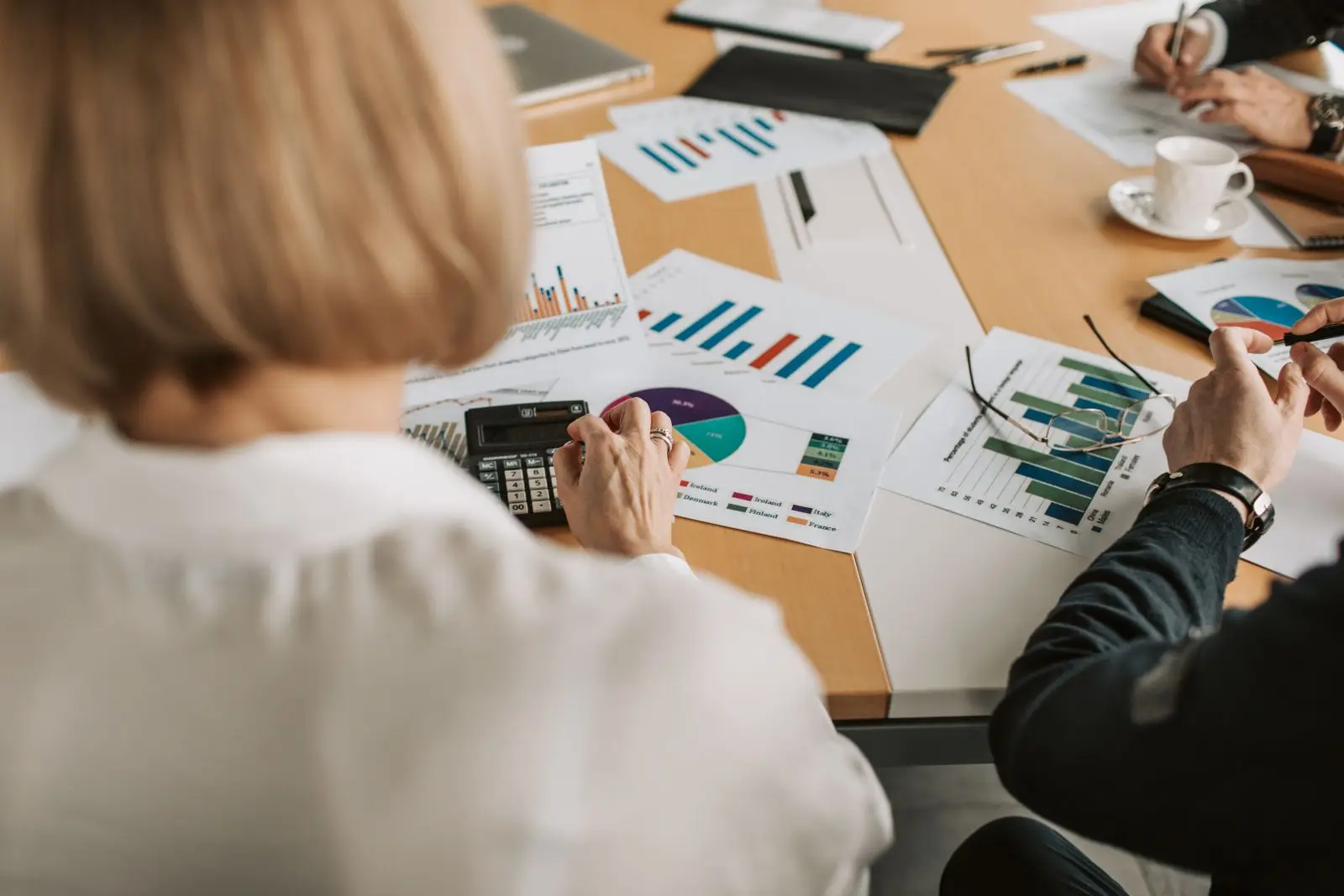 Colleagues review printed charts and figures together at a table.