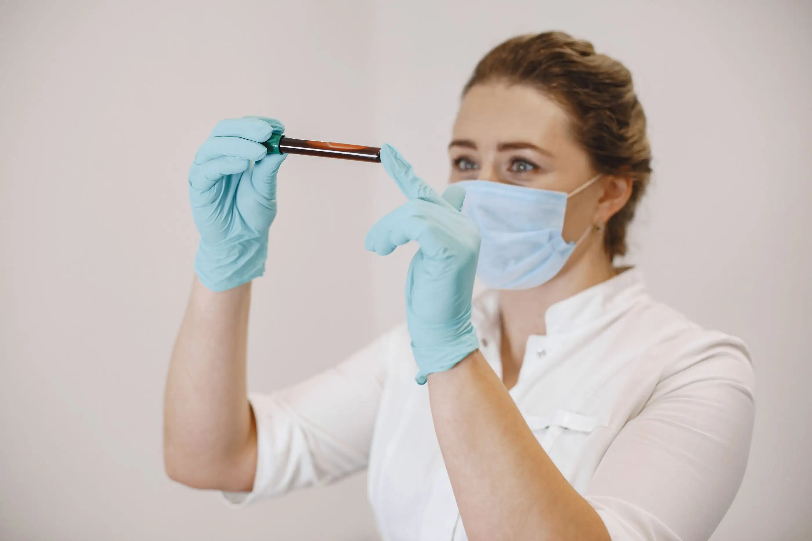 A laboratory worker holds up a blood sample tube.