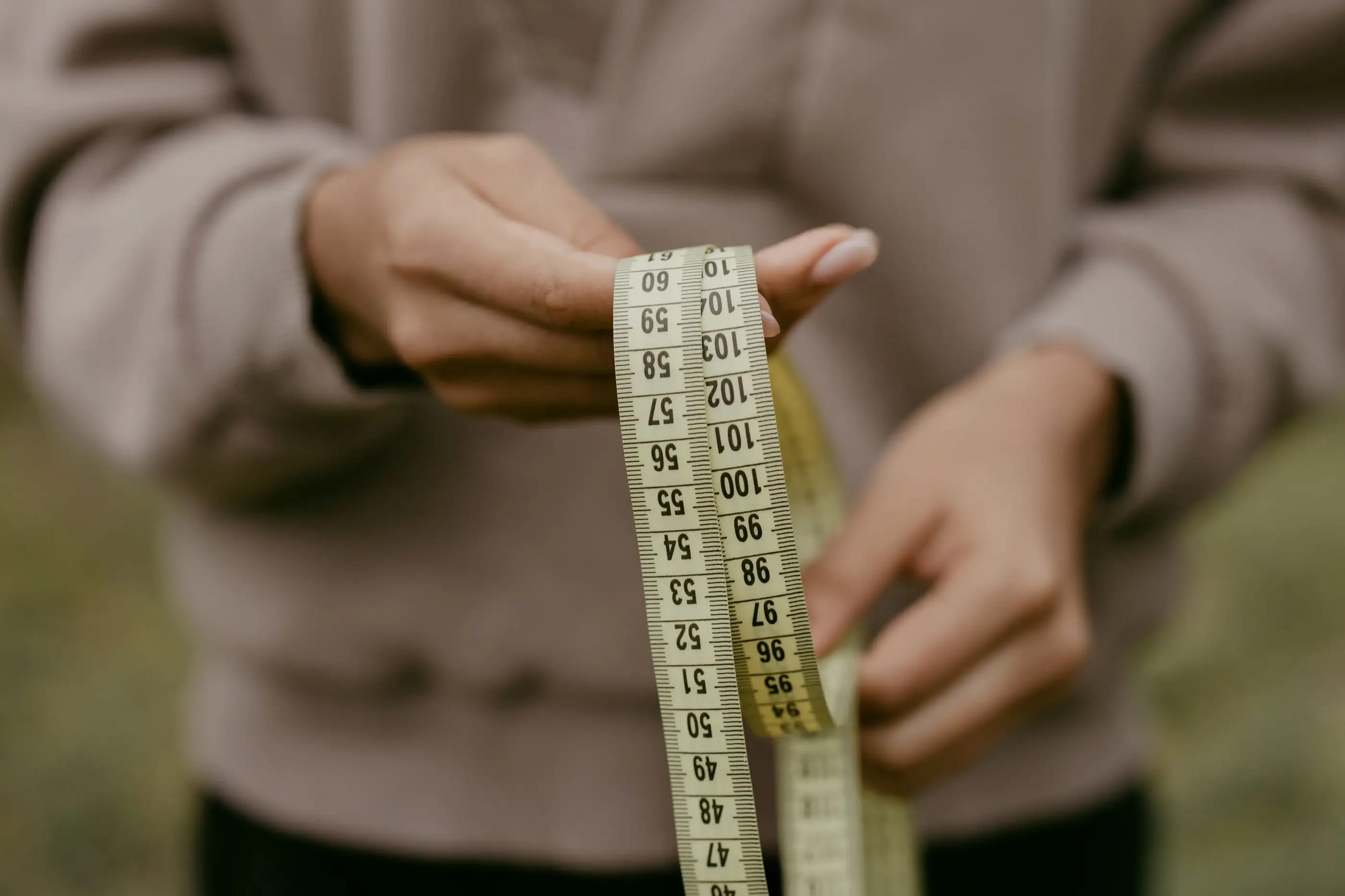 Hands hold a measuring tape.