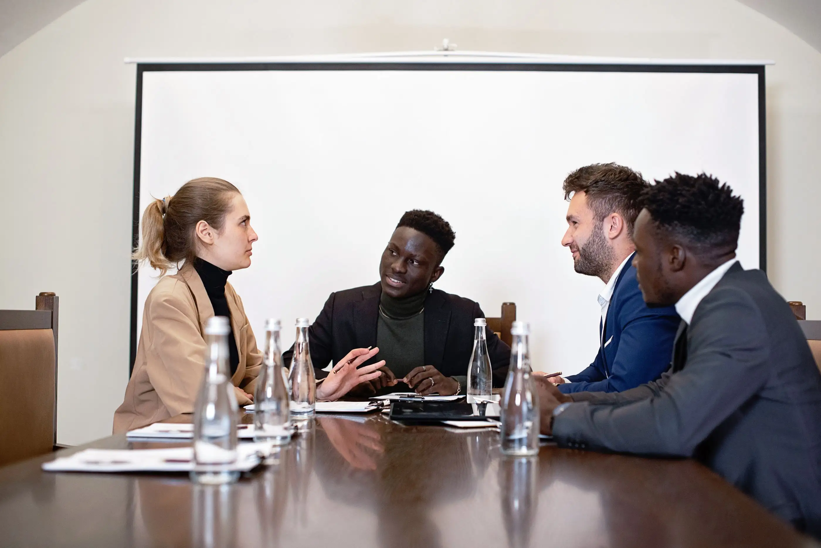 Four colleagues talk around a boardroom table.