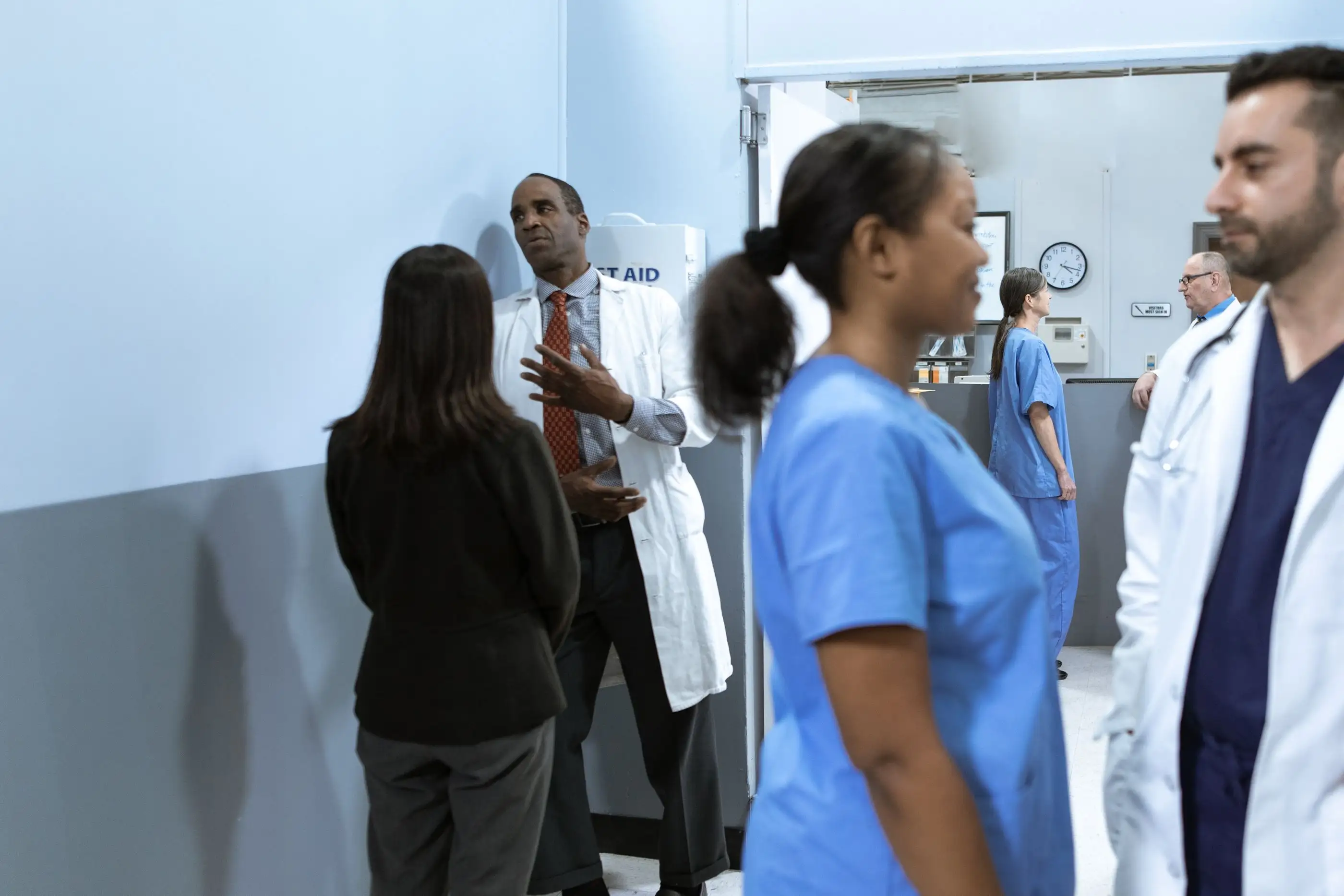 A physician, a nurse and colleagues talk in a hospital corridor.