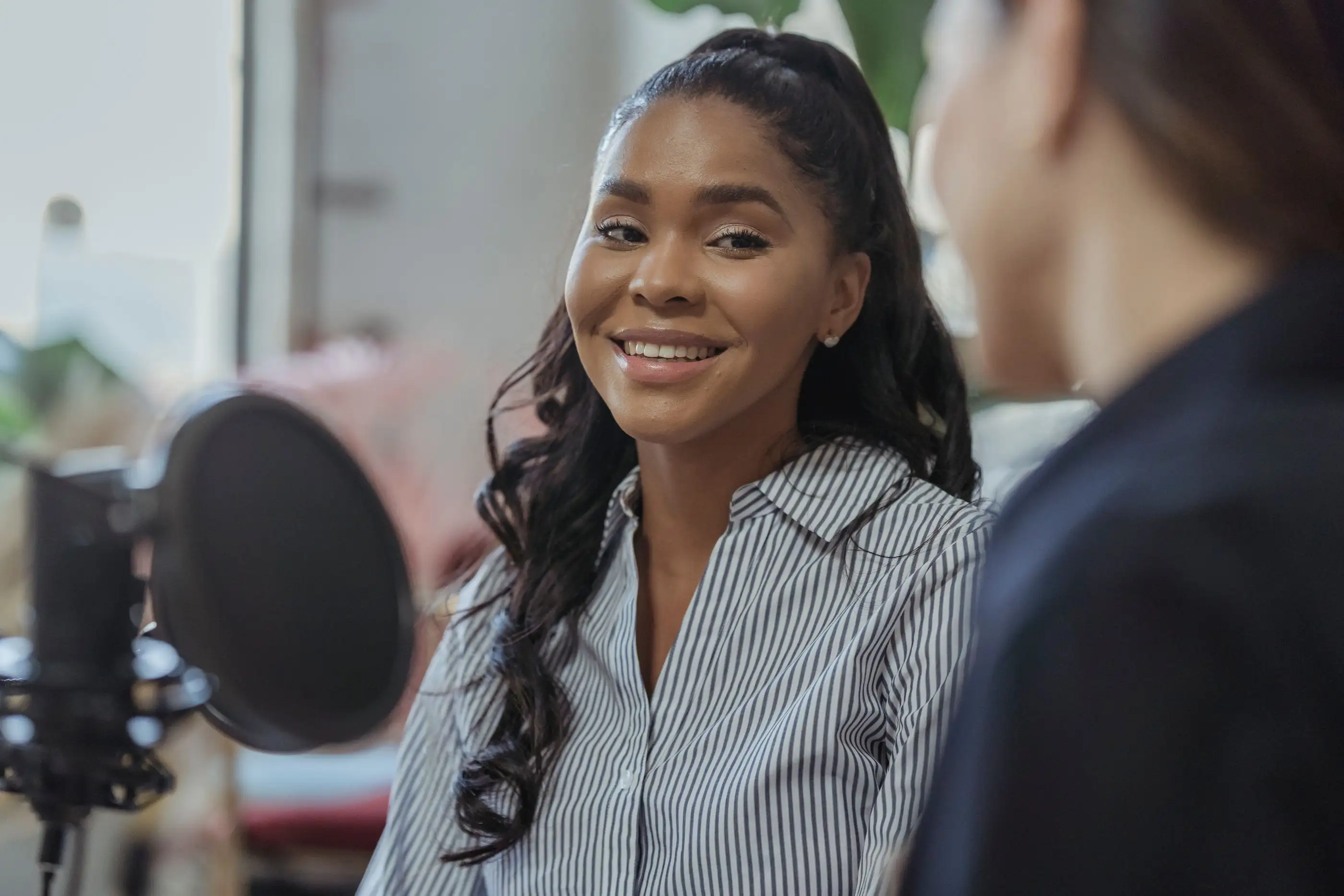A smiling woman speaks into a studio microphone.