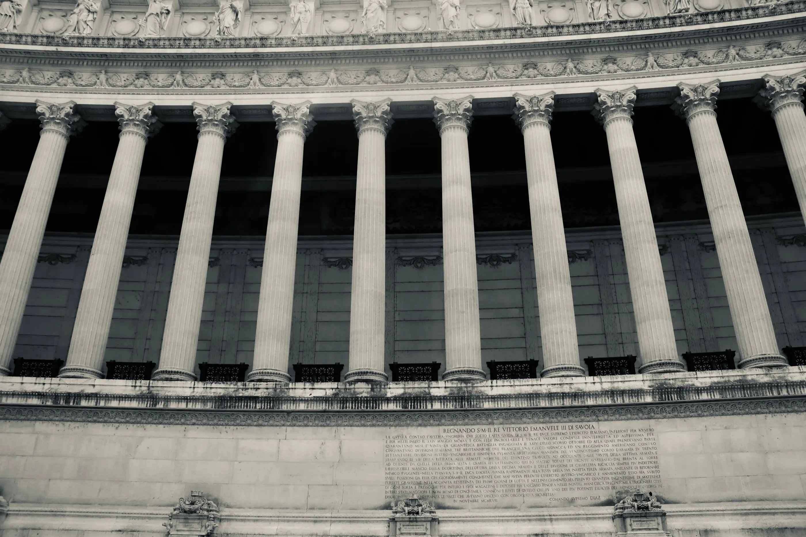 A row of columns along the facade of a public building, seen from below.