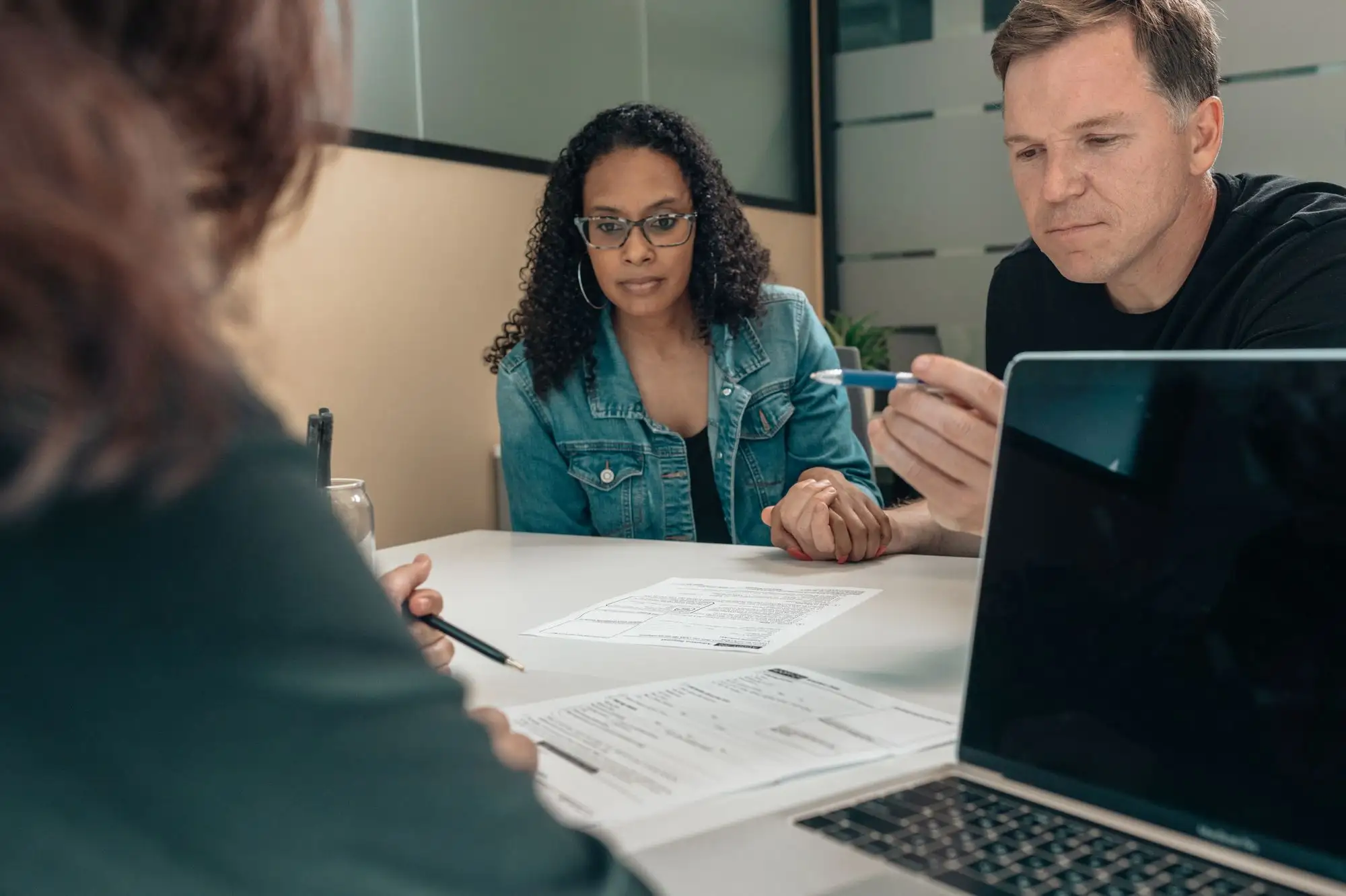 Two colleagues review documents together at a meeting table.