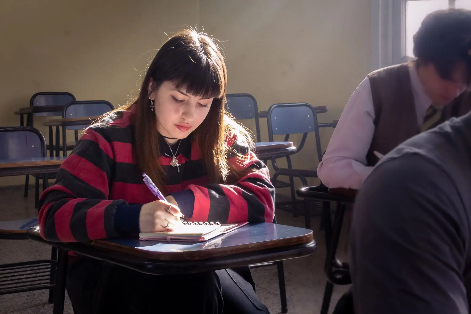 A student writes on an answer sheet in a classroom.