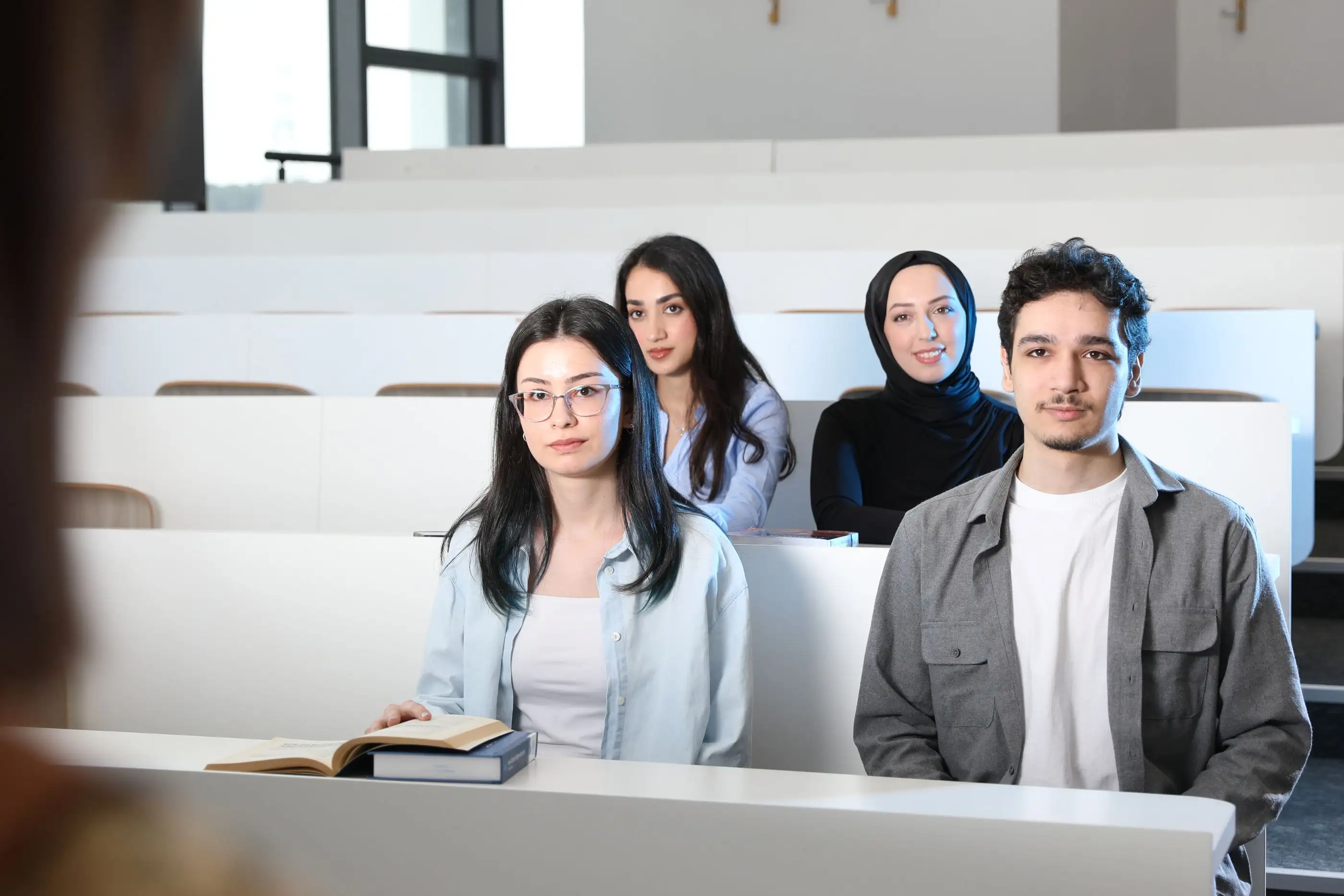 Students sit together in a tiered lecture hall.