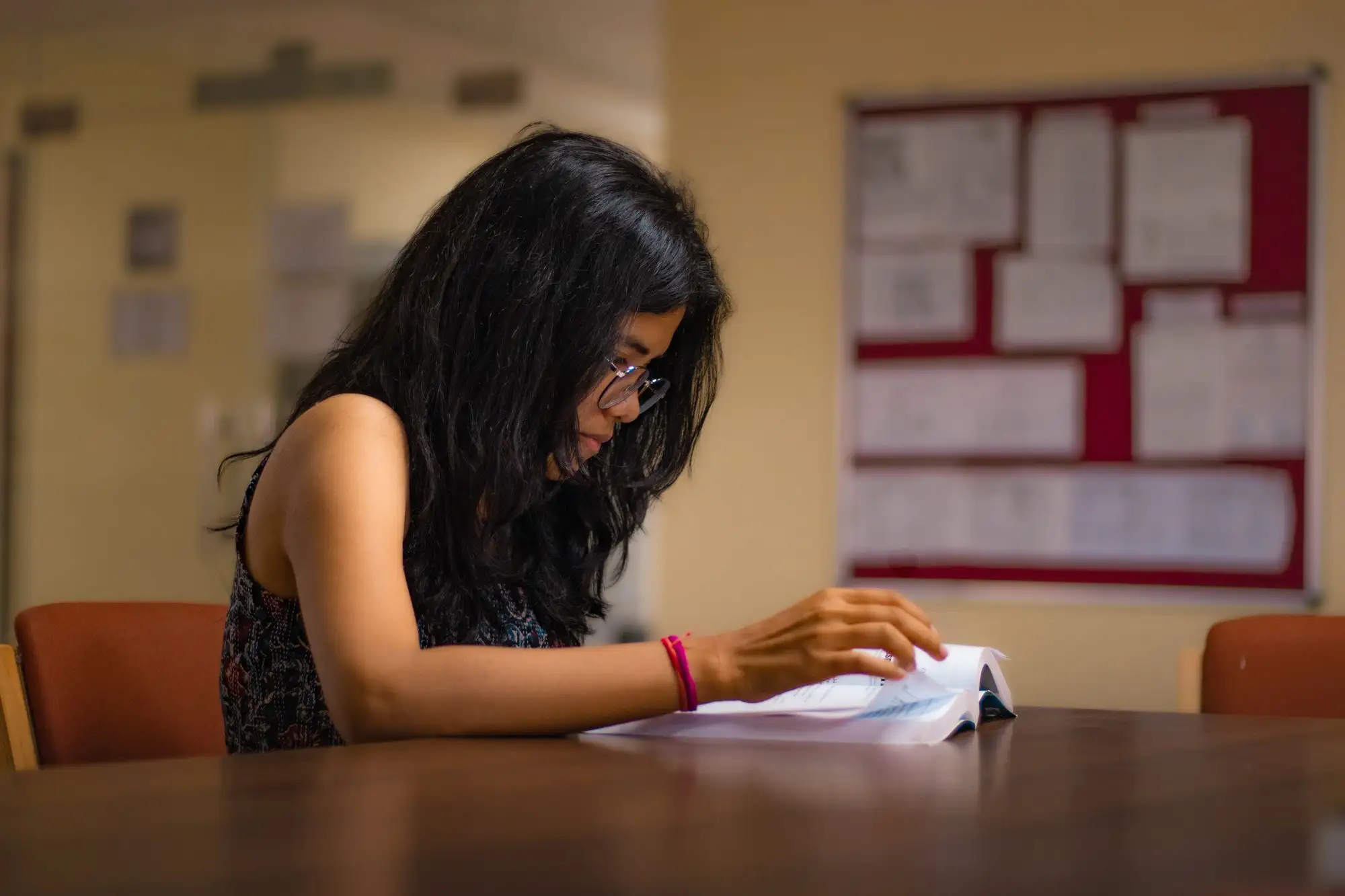 A student reads a book at a library table.