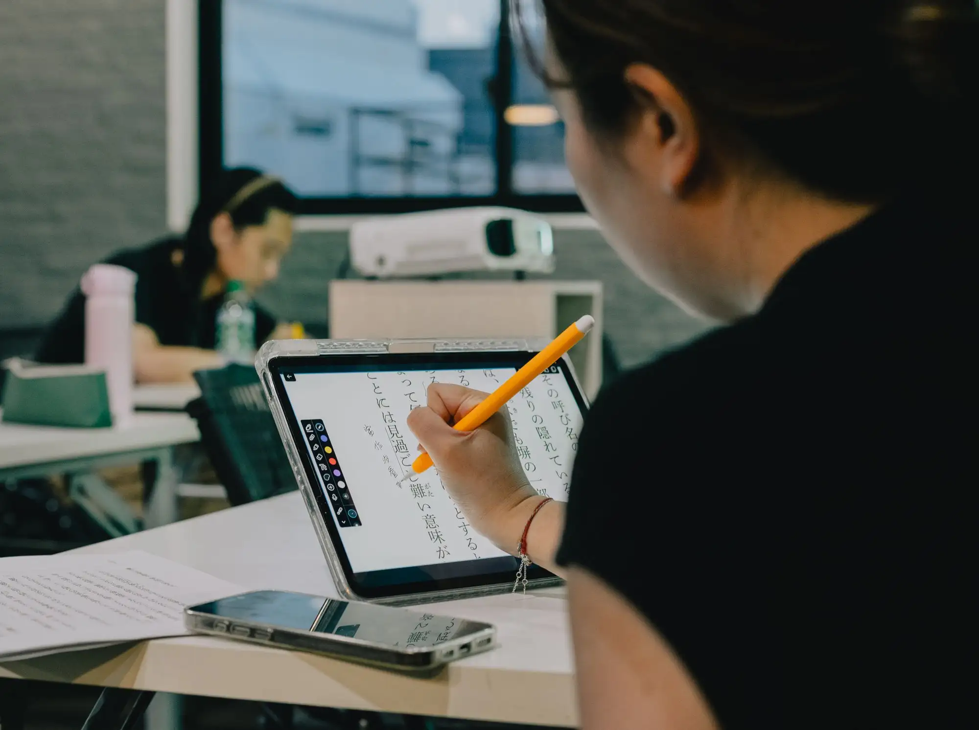 A student takes handwritten notes on a tablet in a classroom.