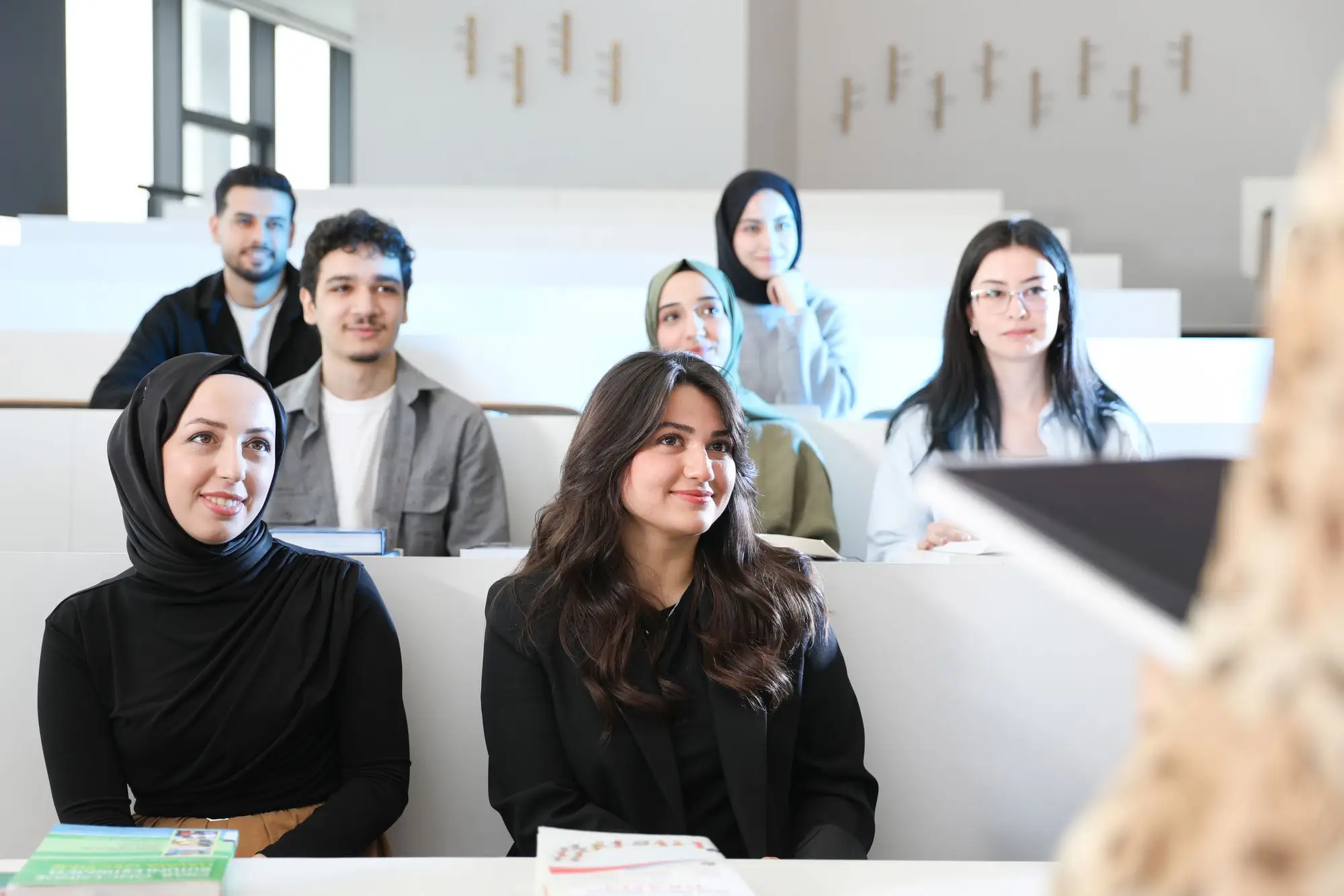 Students smile as they listen in a bright lecture hall.