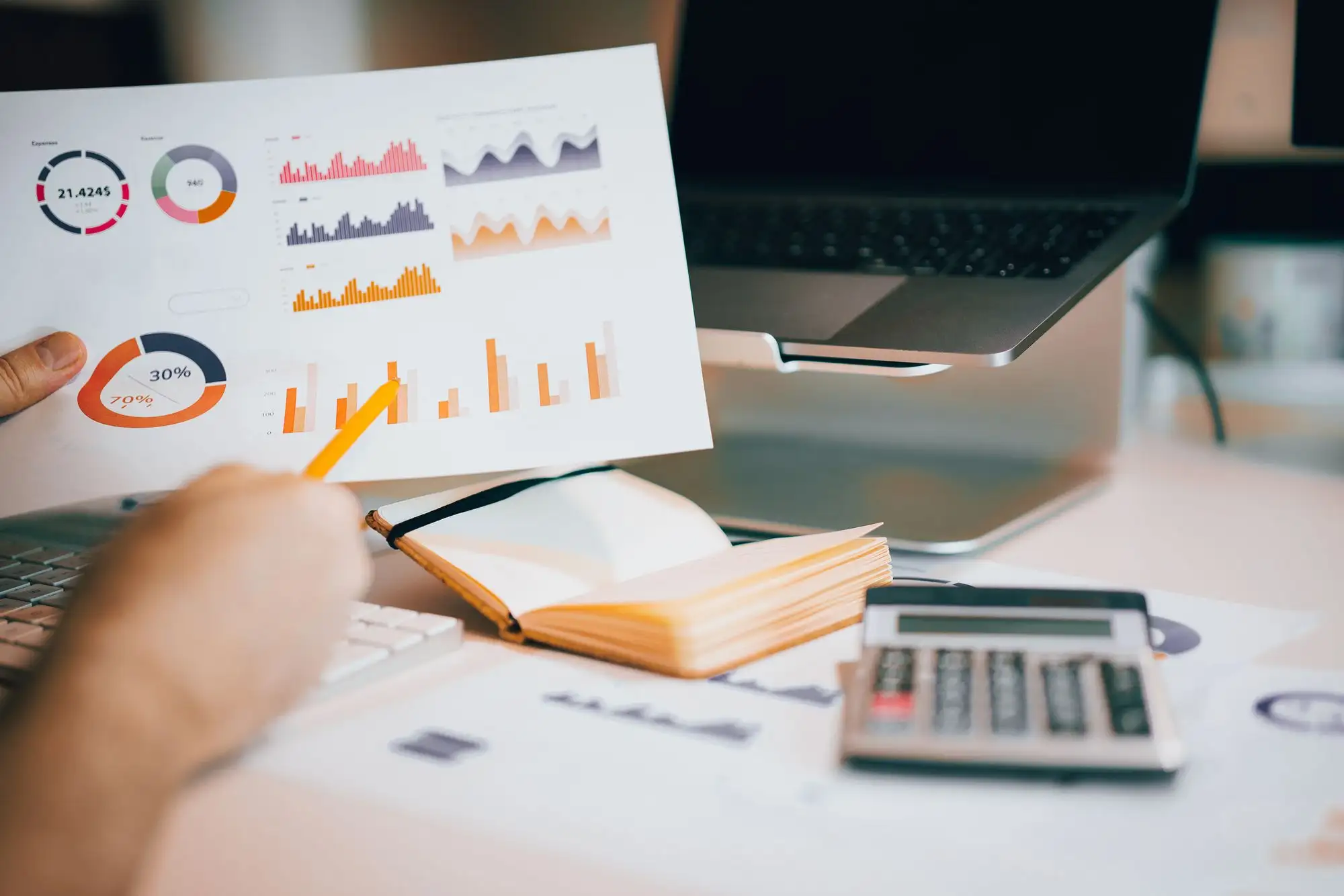 A hand points to a printed chart beside a calculator.