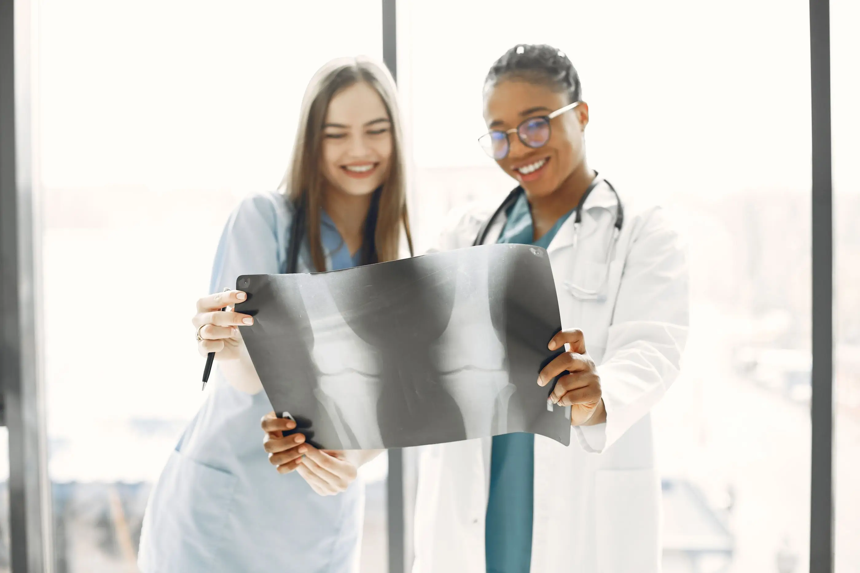 Two smiling clinicians review an X-ray together in a bright room.