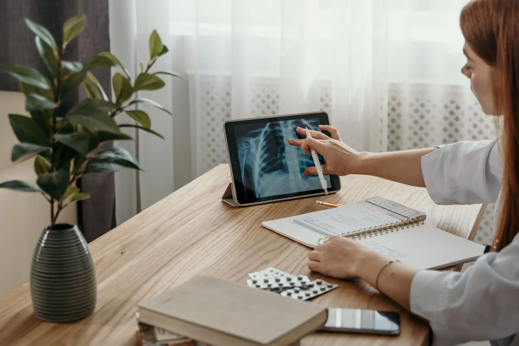 A clinician reviews an X-ray on a tablet at her desk.