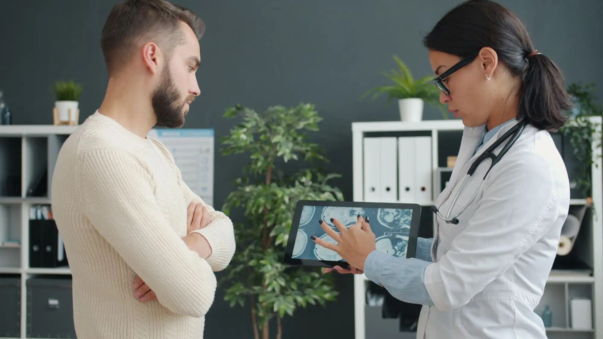 A clinician shows a patient an image on a tablet.