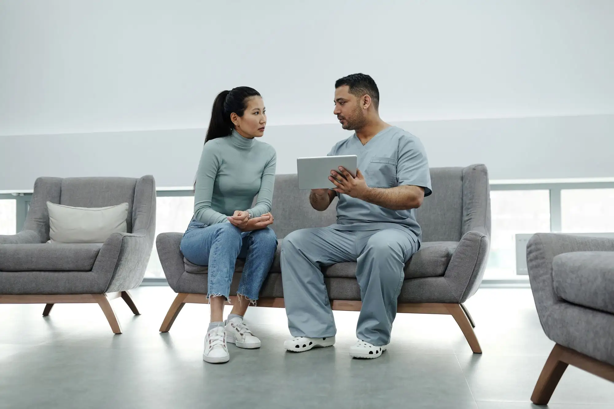 A clinician talks through information on a tablet with a patient in a waiting area.