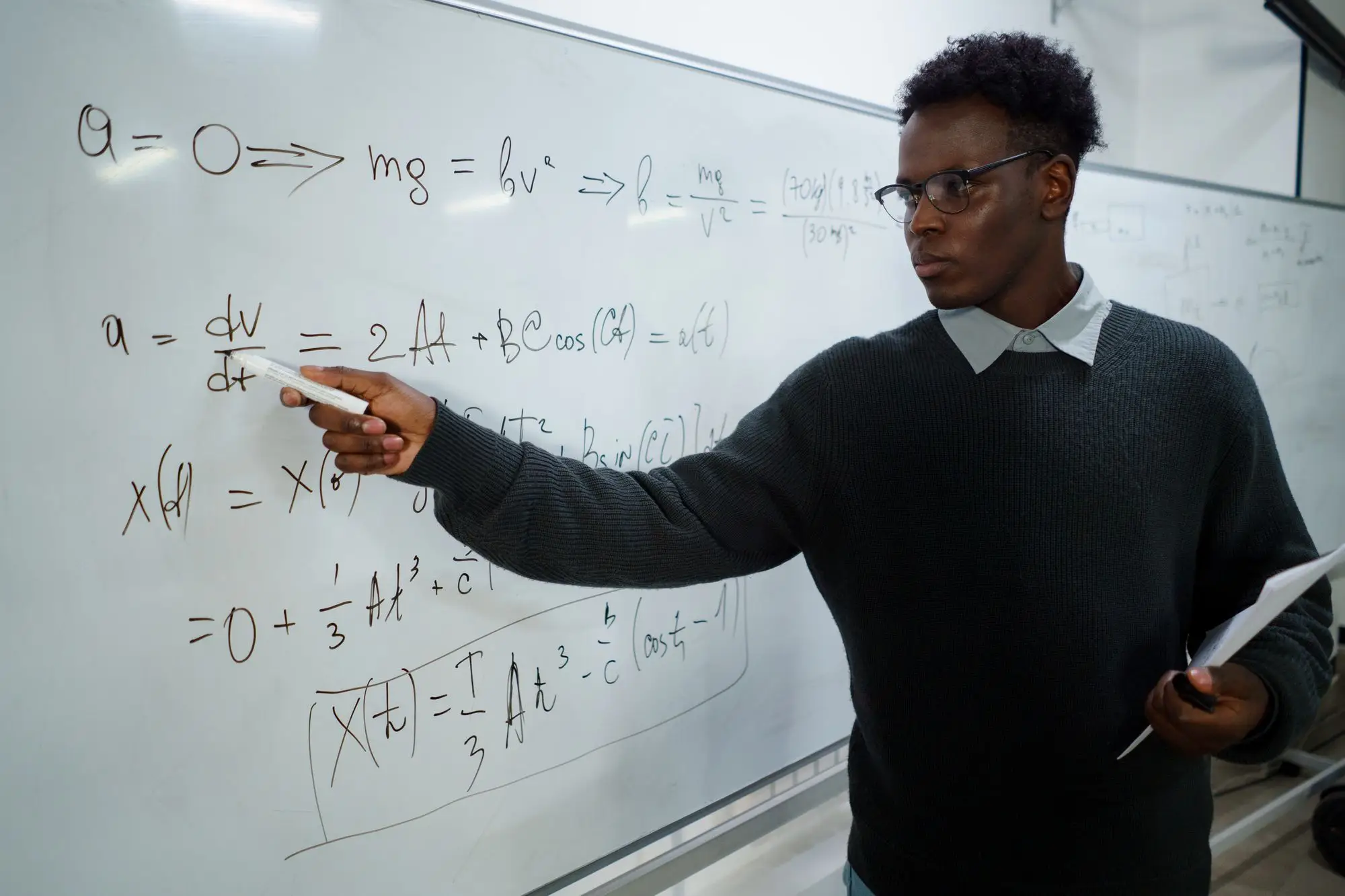 A lecturer explains equations on a whiteboard.