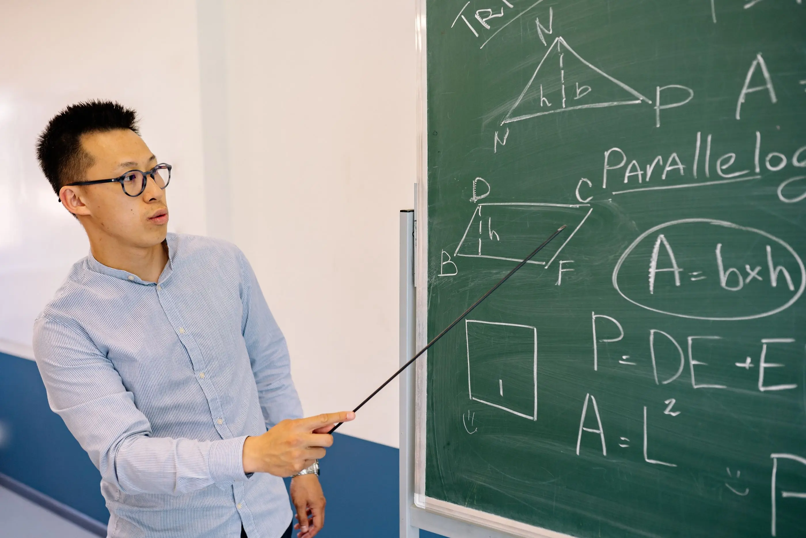An educator points to geometry formulas on a chalkboard.