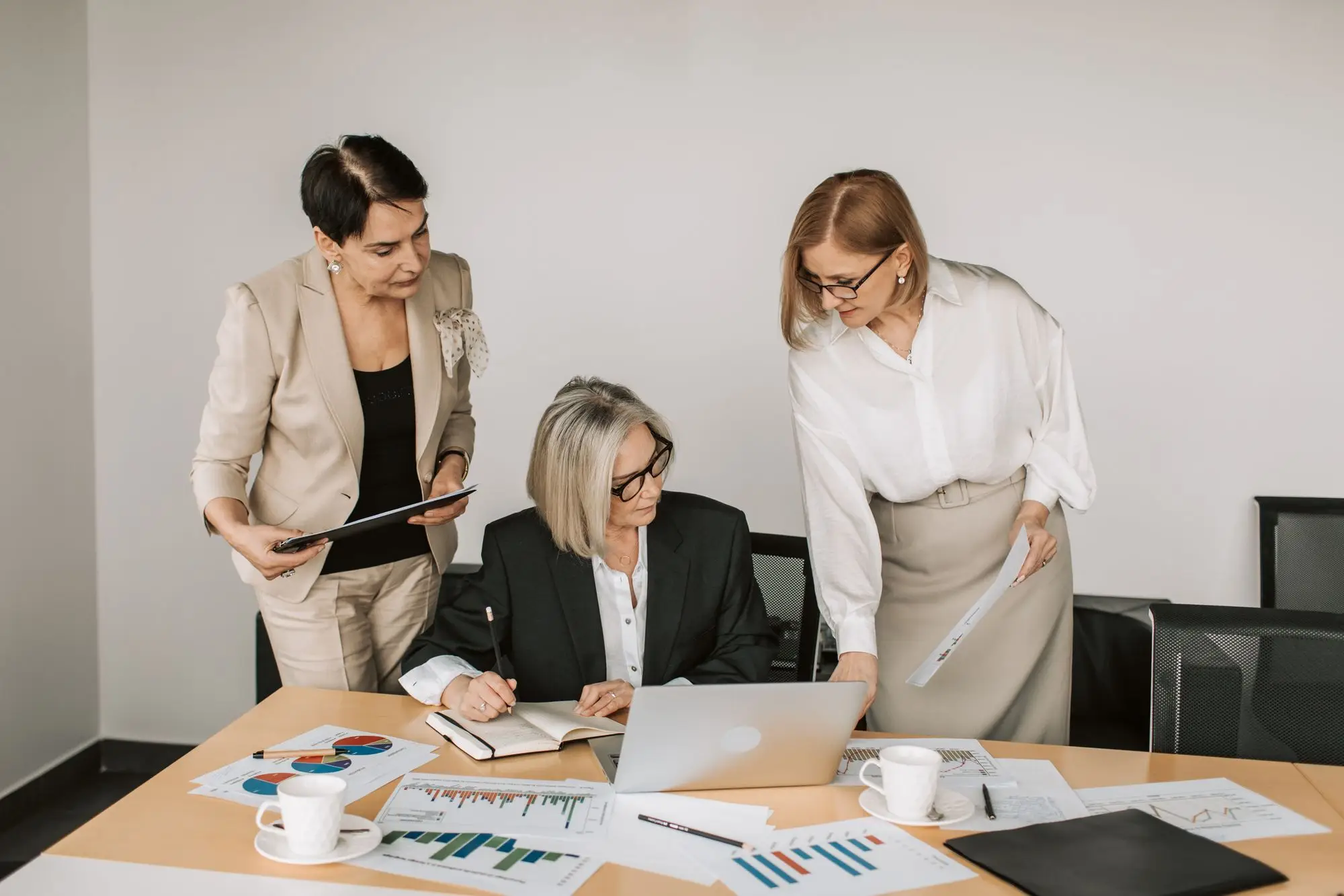 Three leaders review charts and reports around a meeting table.