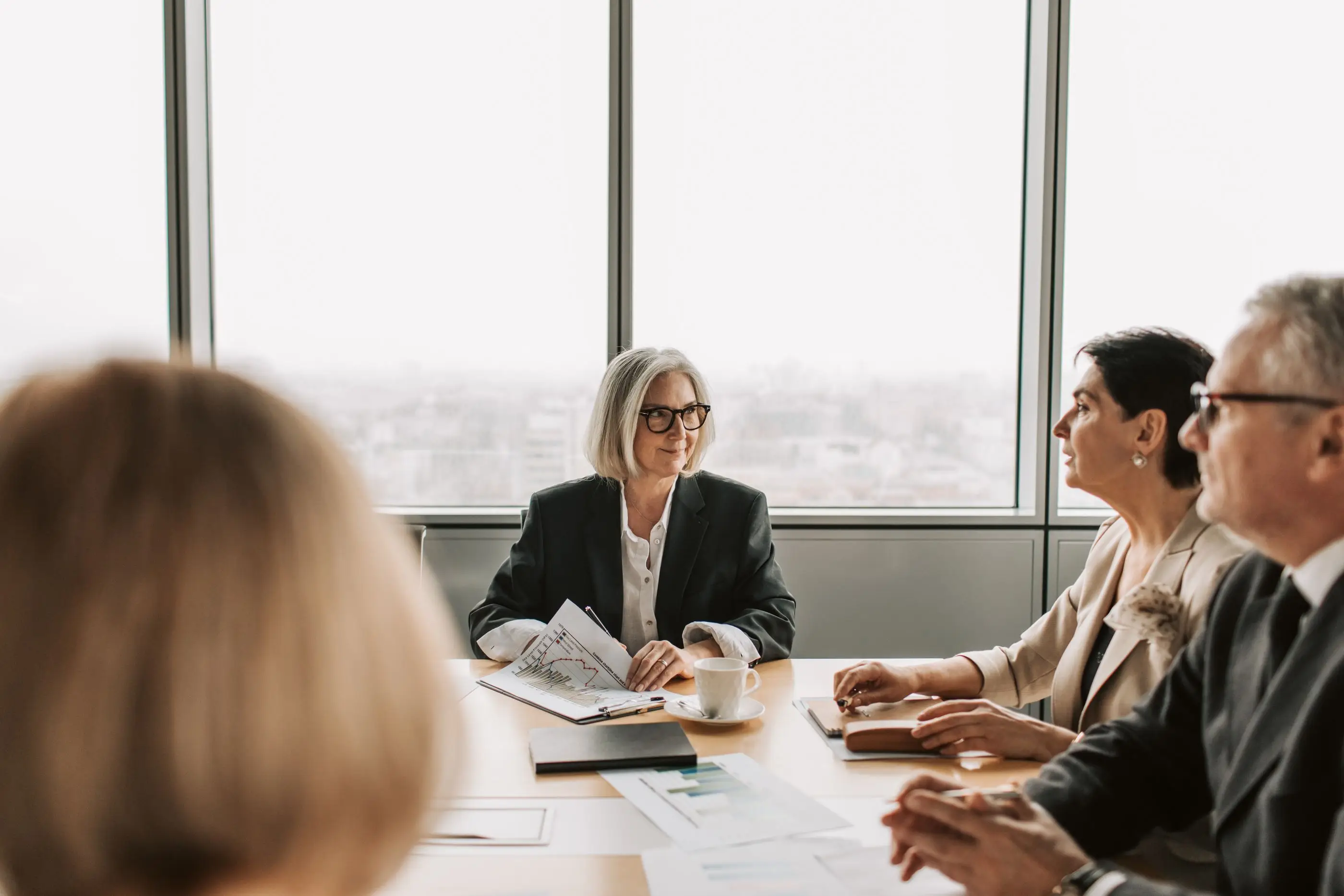A leader chairs a meeting with colleagues in a bright boardroom.