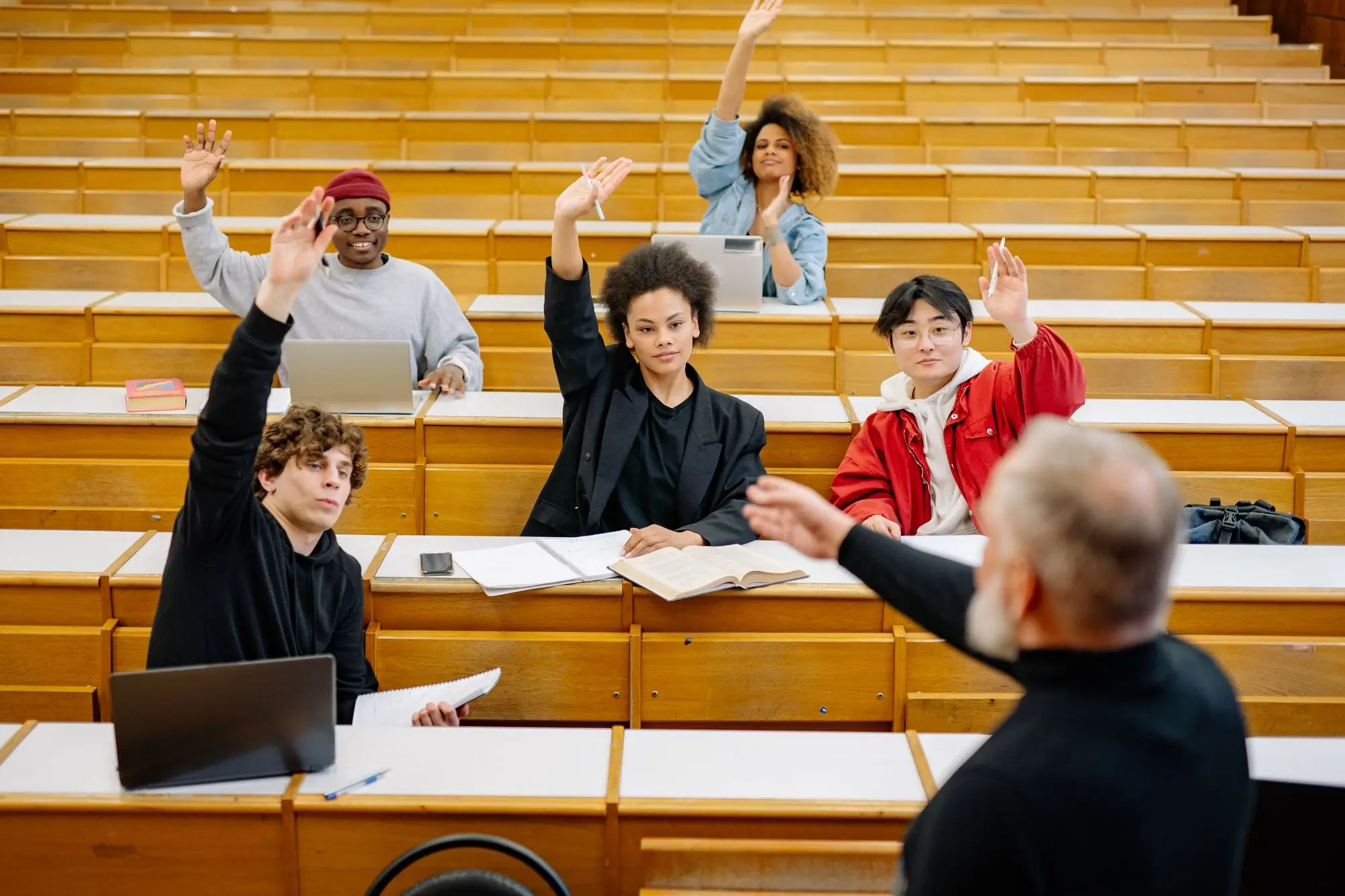 Students raise their hands to answer a lecturer's question.