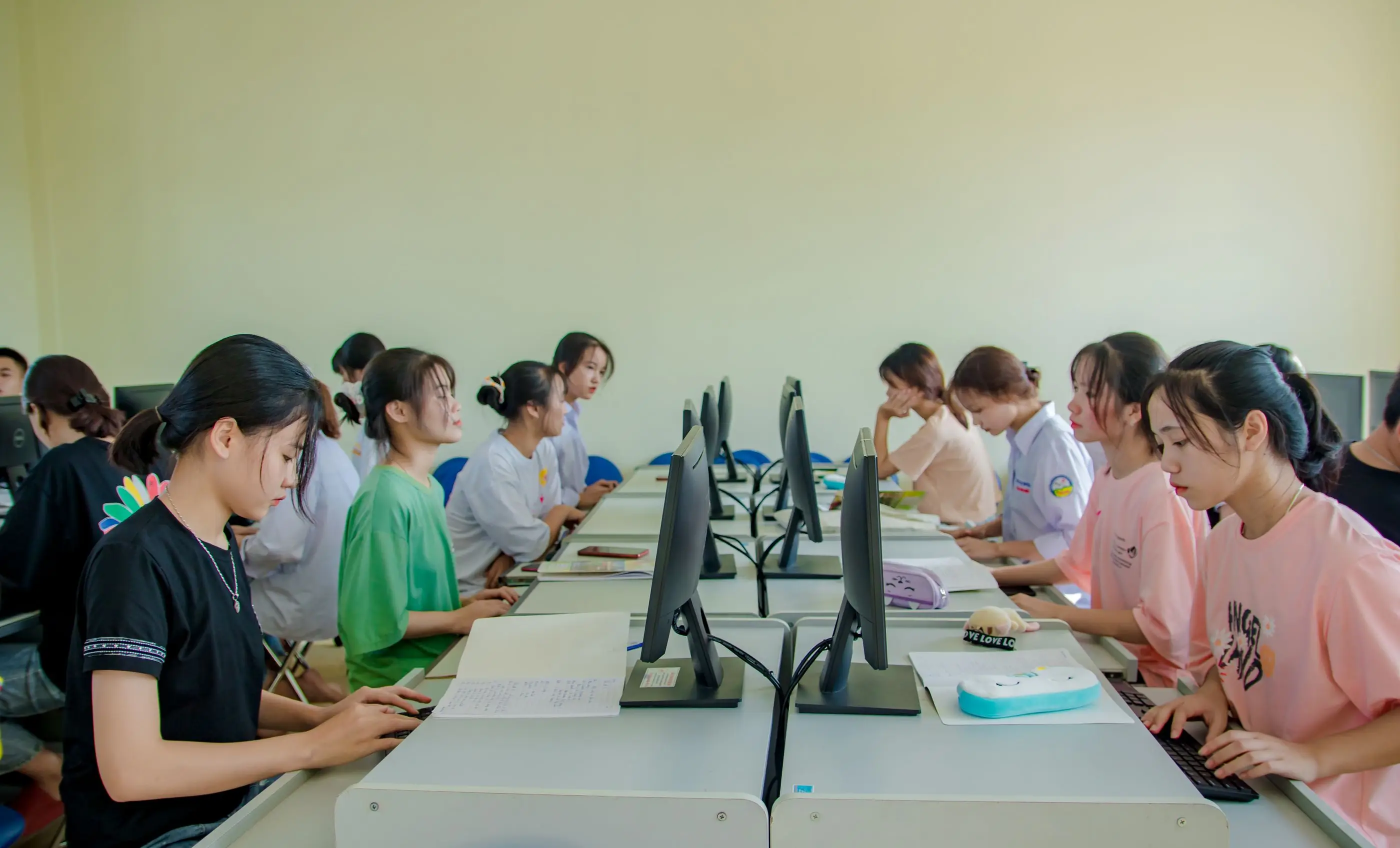 Students work side by side at computers in a teaching lab.