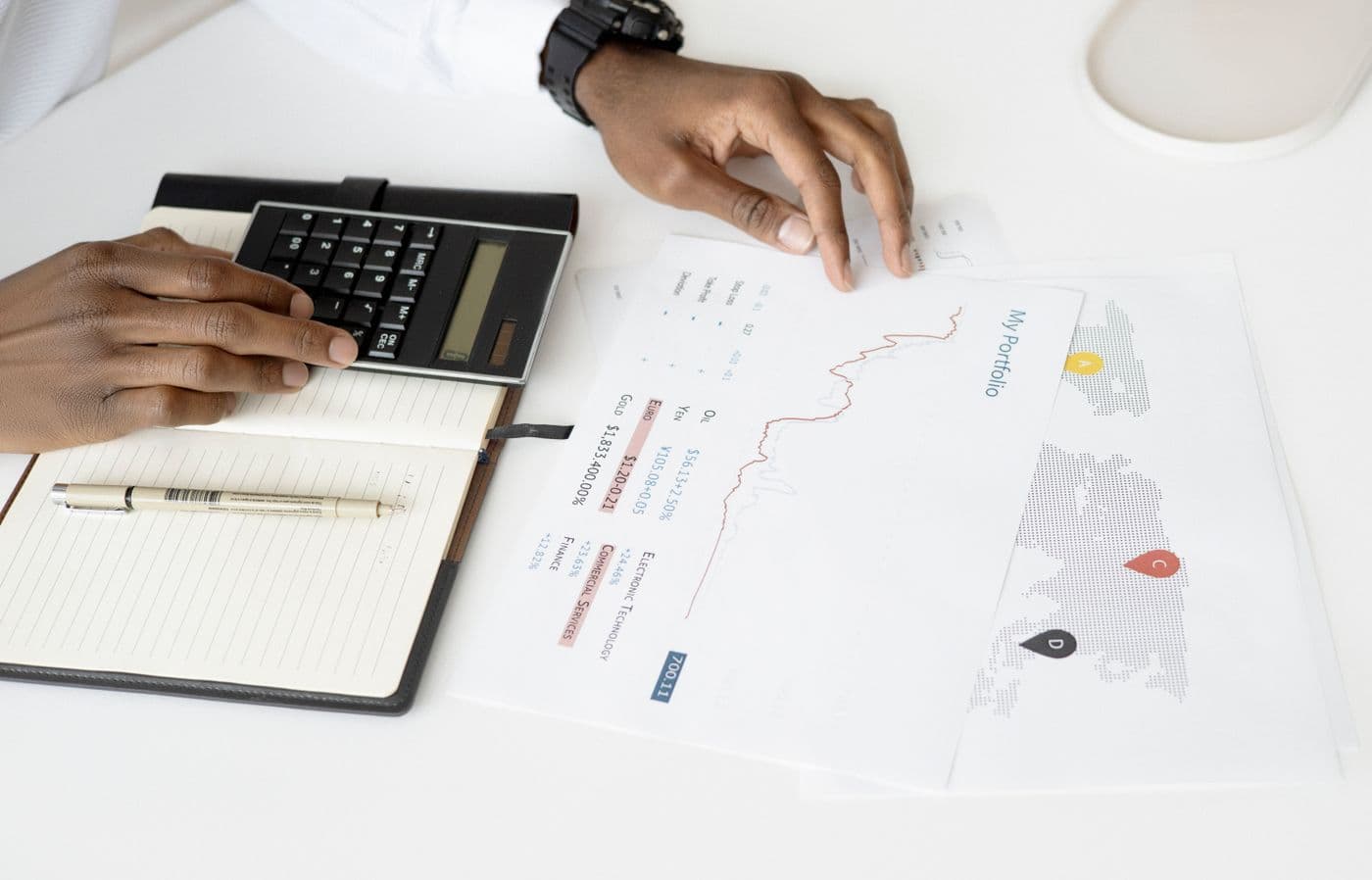 A person works through figures on a calculator beside printed charts.