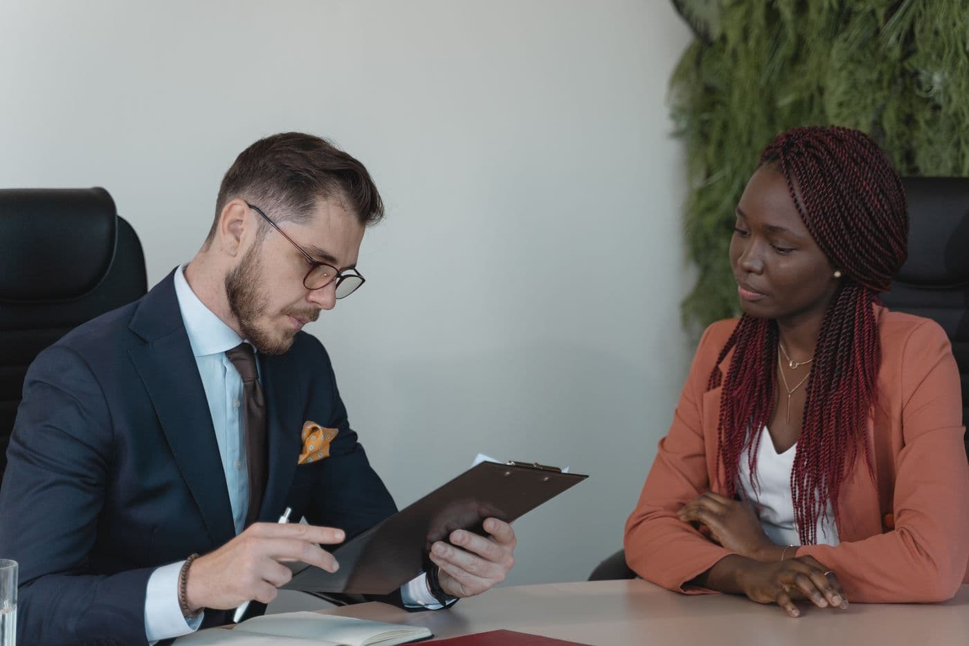 An interviewer reviews a candidate's resume across a desk.