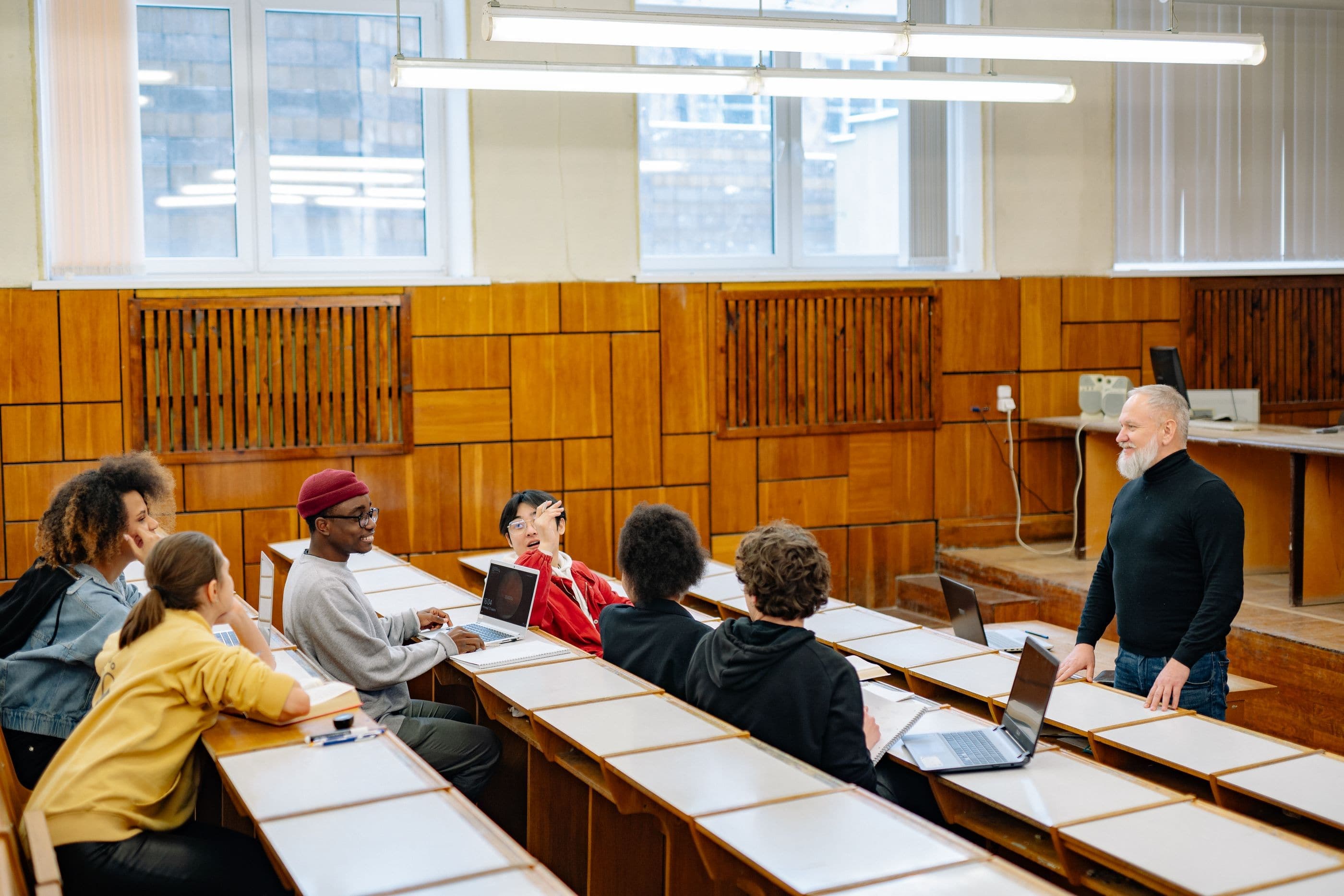 Adult learners talk with an instructor in a lecture hall.