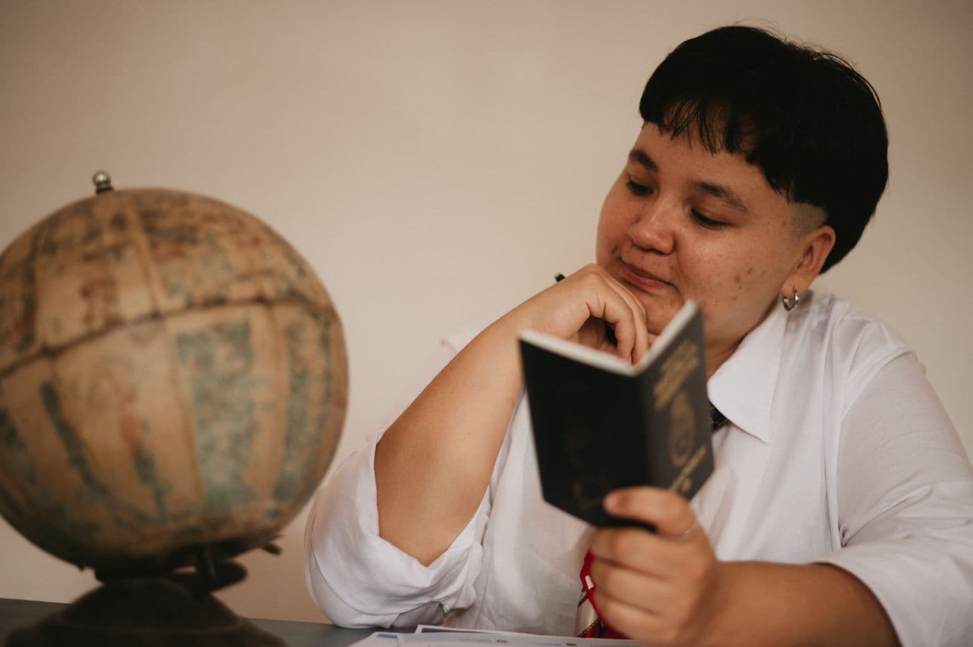 A young person reads a passport beside a globe.