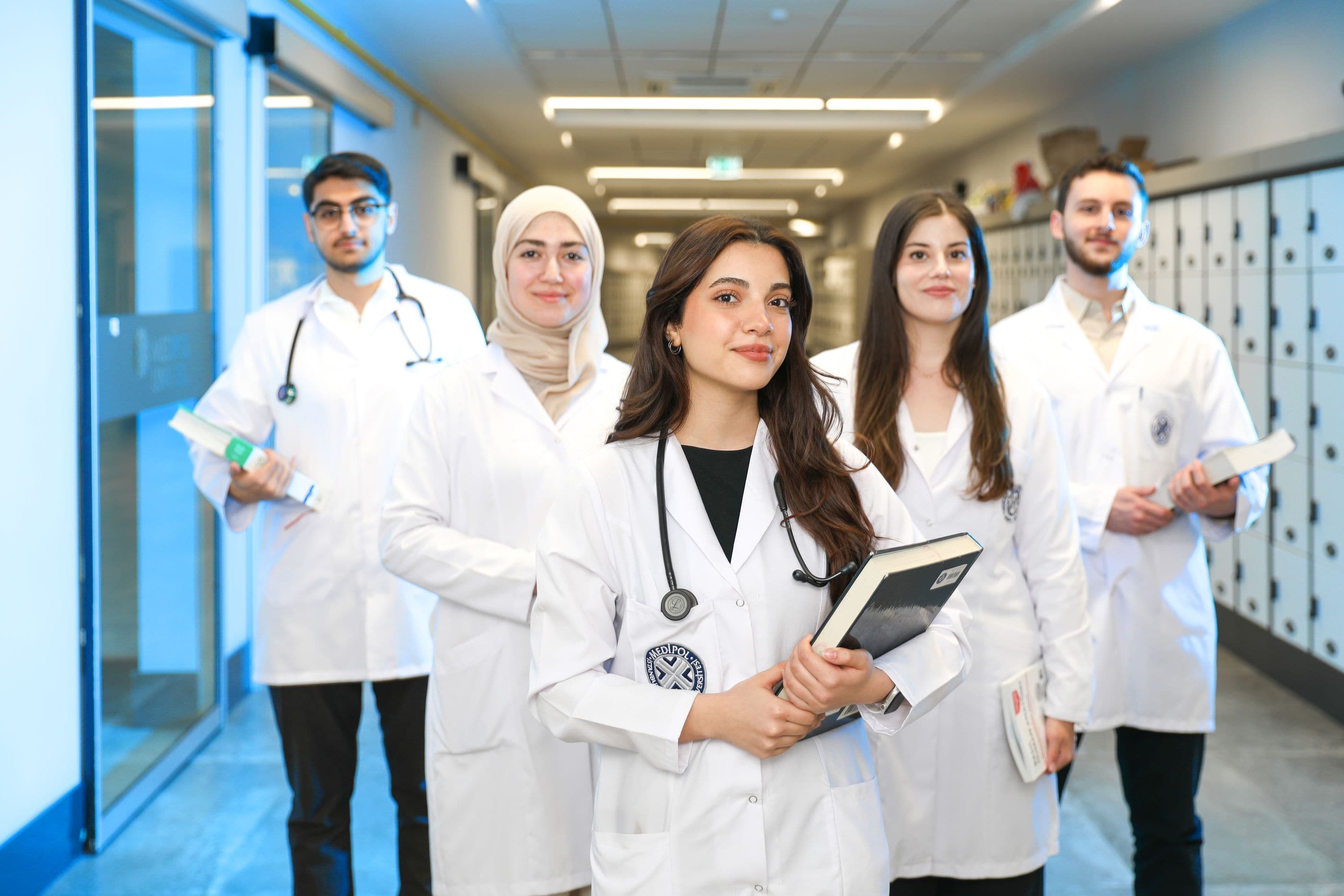 Students in white coats walk together down a bright corridor.