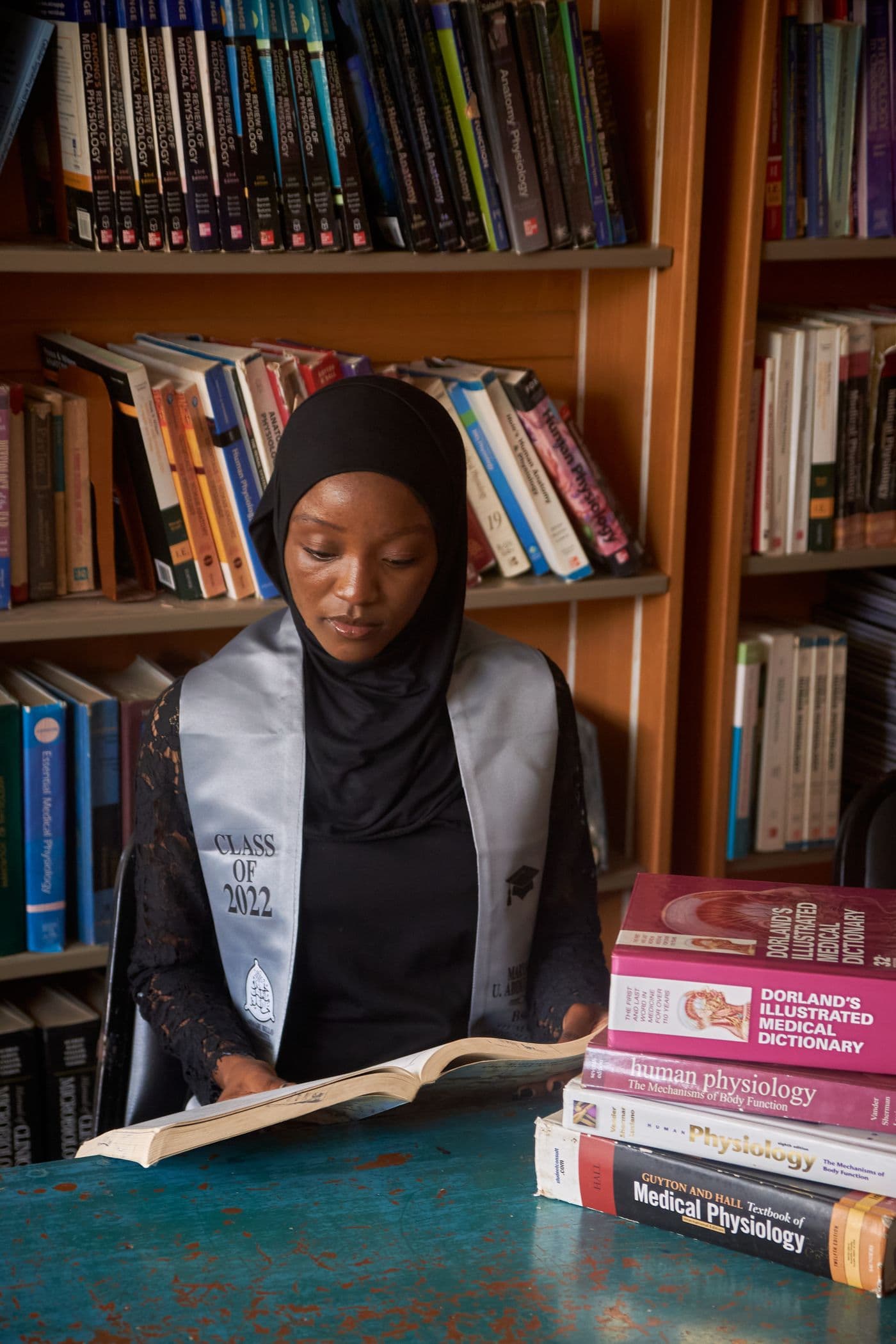 A graduate studies at a library table stacked with licensing textbooks.